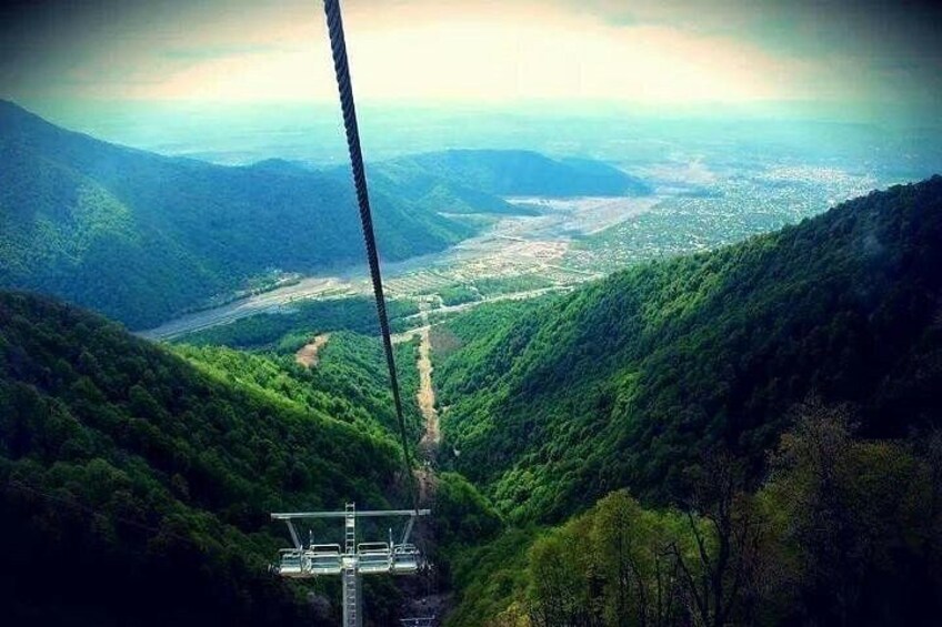 A cable car system in a mountainous area with lush greenery and a valley below. 4