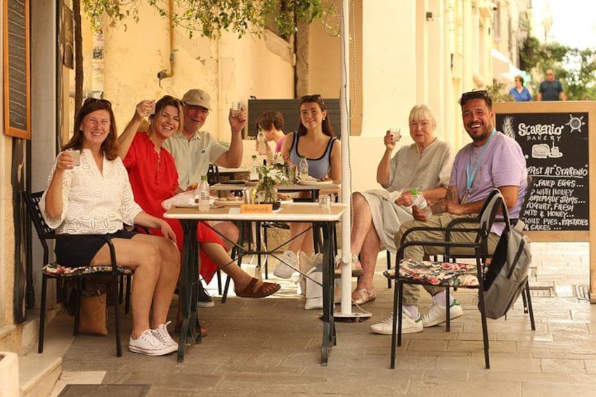 Un grupo de personas sentadas en un café al aire libre con una pizarra de menú al fondo. 1