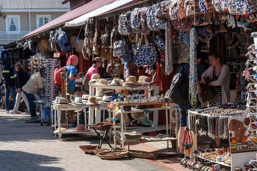 A bustling outdoor market with various stalls selling hats, bags, and jewelry. 5