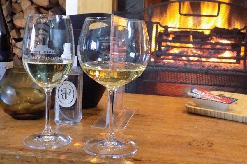 Two wine glasses on a wooden table with a fireplace in the background. 4