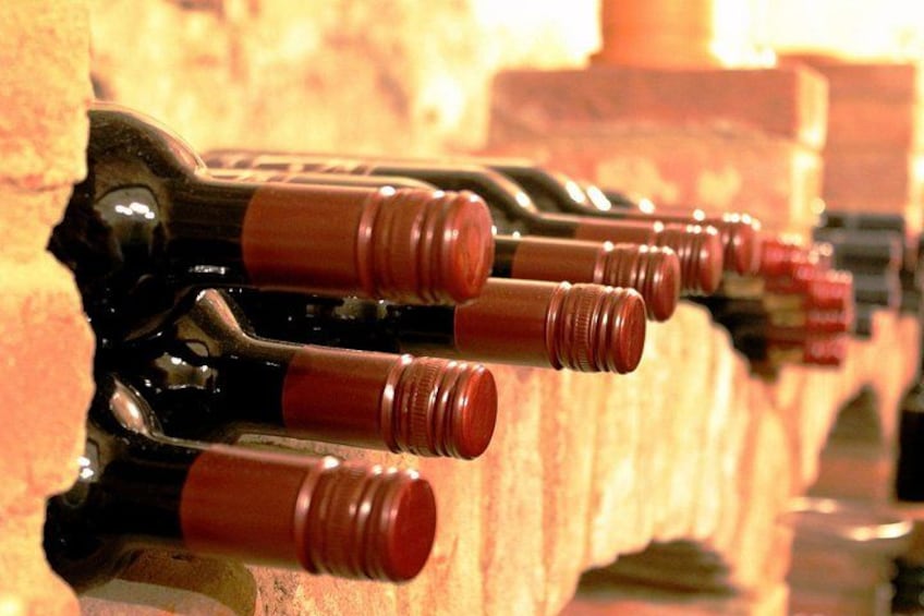Botellas de vino en fila con corchos, dispuestas en un mueble de madera. 3