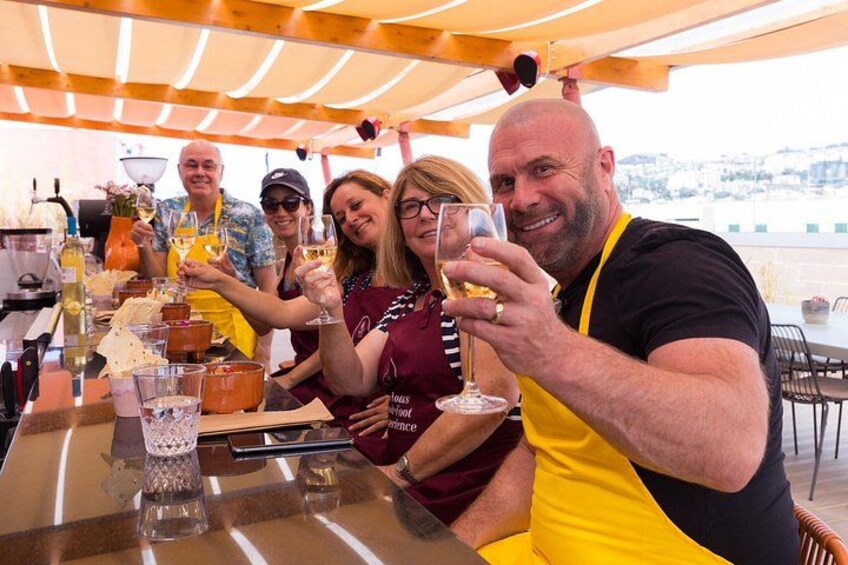 A group of people toasting with drinks at an outdoor table with a city view. 4