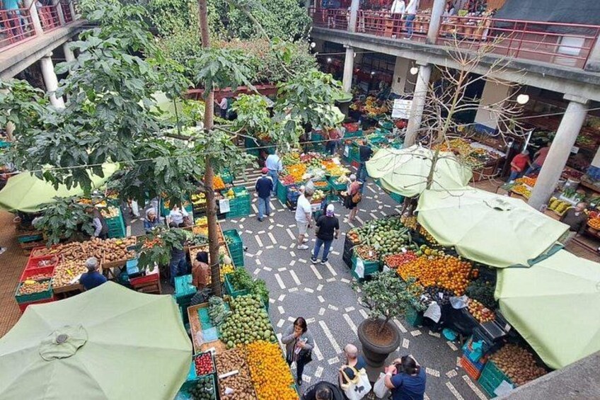 An outdoor market with various stalls selling fruits and vegetables. 2
