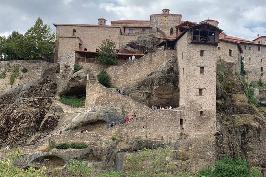 A historic stone building with a steep staircase and a large rock formation. 5