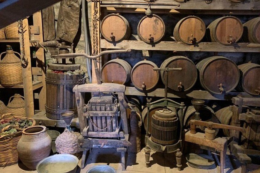 A cellar with wooden barrels, a cider press, and various containers. 3
