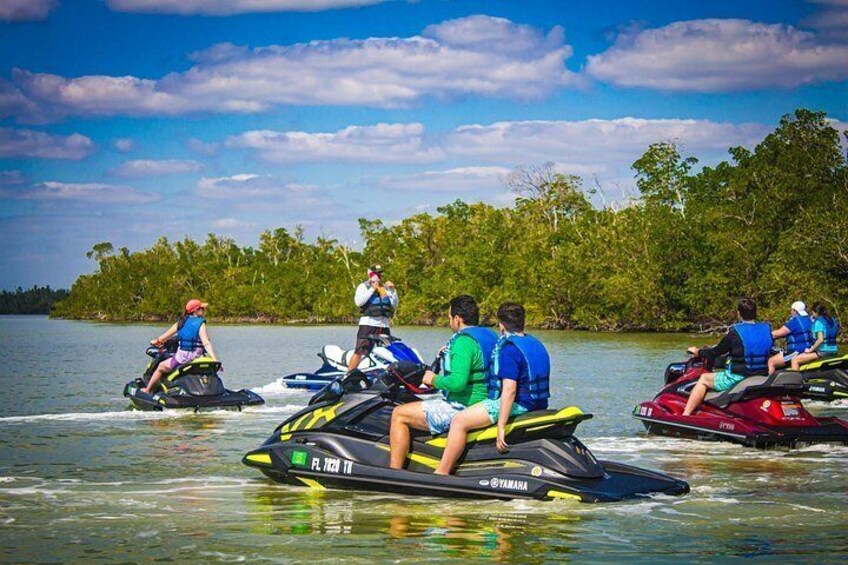People jet-skiing on a lake surrounded by trees. 2