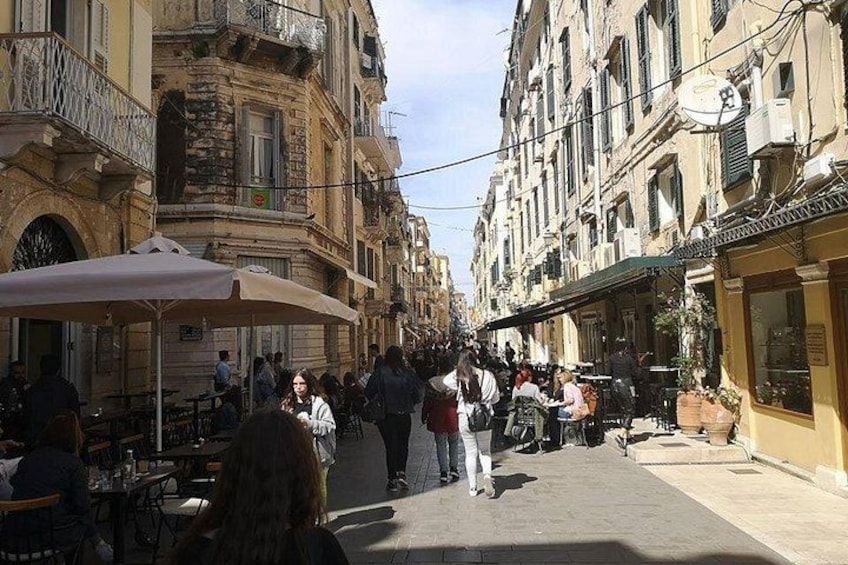 A busy street with outdoor cafes, pedestrians, and historic buildings. 5