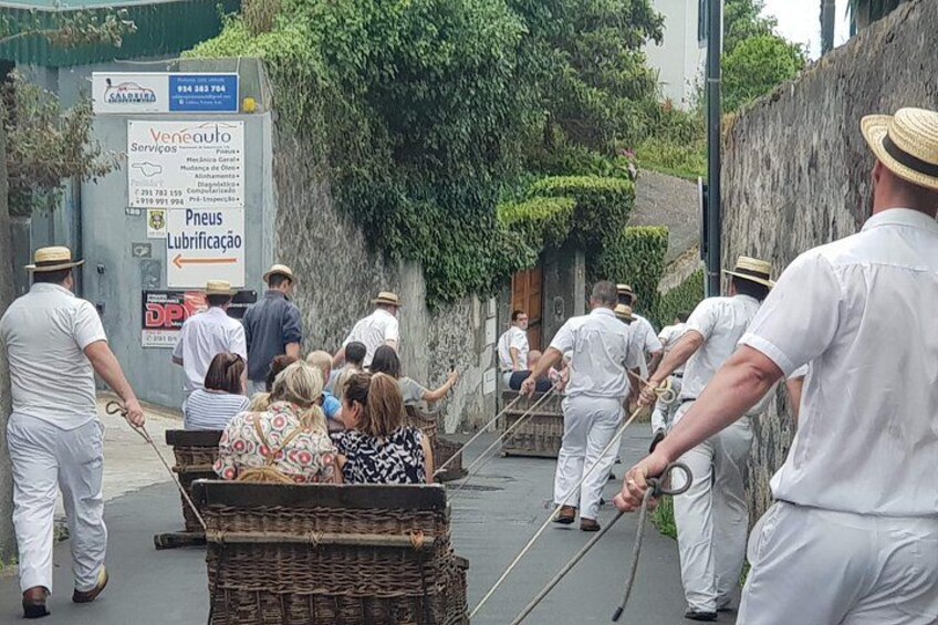 A group of people in white uniforms pulling a cart down a street. 5