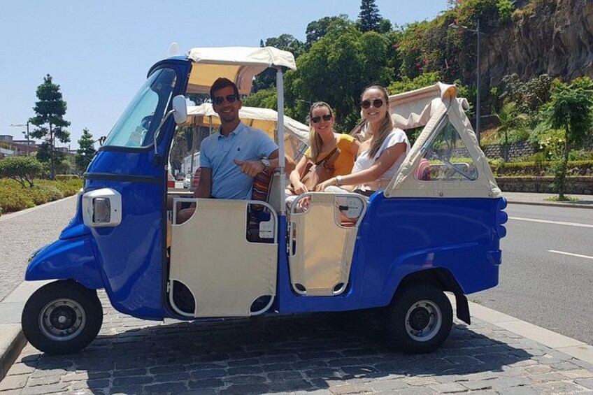 A blue and white three-wheeled vehicle with passengers. 3