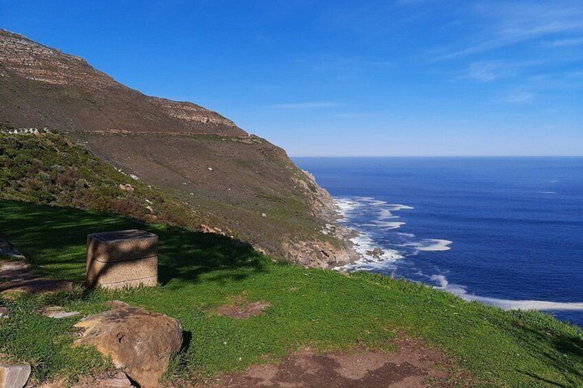 A coastal landscape with a grassy hill, a rocky outcrop, and the ocean. 5