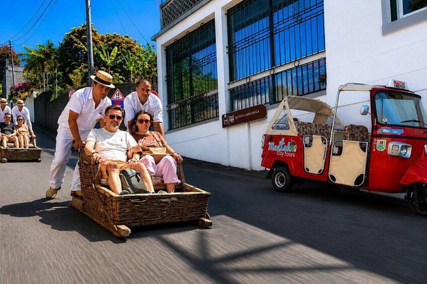 Ein Korbbus mit Fahrgästen, ein rotes Tuk-Tuk und ein Gebäude mit einem Schild. 1