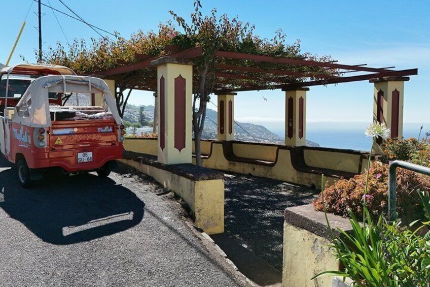 A red van parked near a coastal structure with a view of the ocean. 5