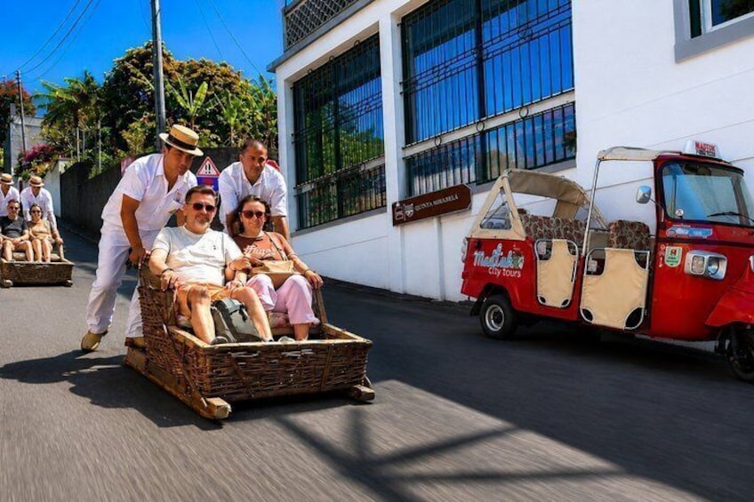 A wicker cart with passengers, a red tuk-tuk, and a building with a sign. 1