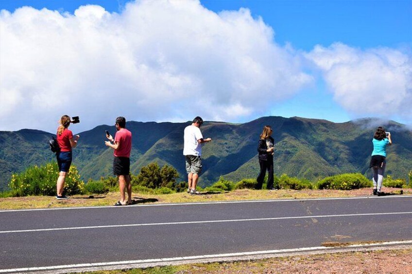 Un grupo de personas parada al borde de la carretera, tomando fotos de una cordillera. 3
