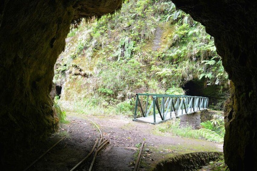 A cave entrance with a metal bridge over a dirt path. 3