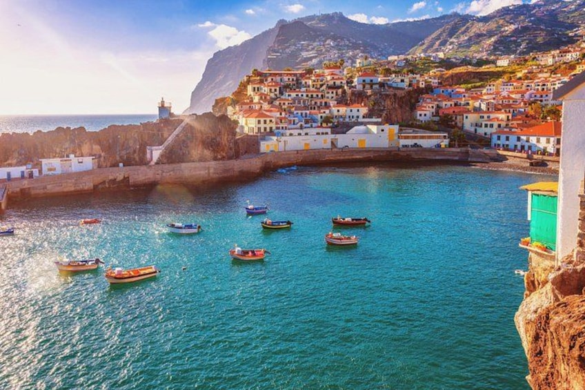 A coastal town with boats on the water, buildings on a cliff, and a lighthouse in the distance. 1