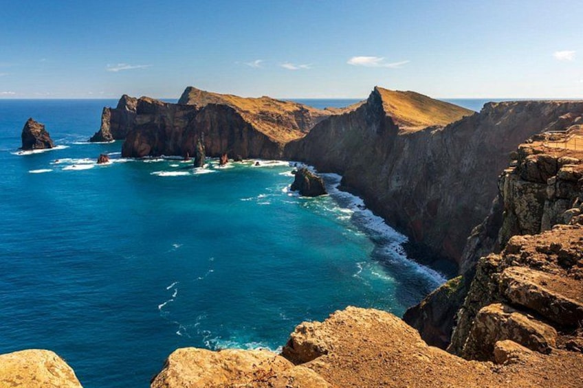 A coastal landscape with cliffs, a clear blue sea, and rocky outcrops. 5
