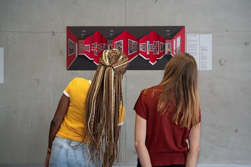 Two people viewing a red and black artwork on a wall. 2