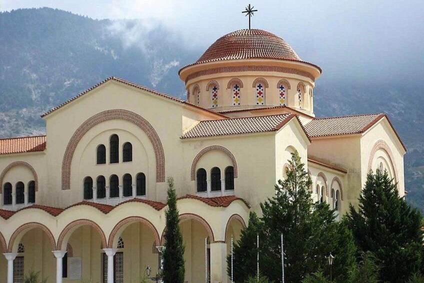 Une église dotée d’un dôme et de fenêtres en arc de cercle, entourée d’arbres et de montagnes. 1