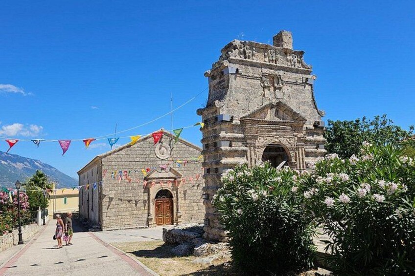 Une église en pierre dotée d’un clocher, entourée de verdure et surplombée d’un ciel bleu clair. 4