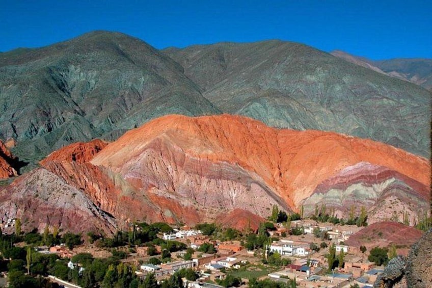 A town nestled in a valley with colorful mountain ranges in the background. 1