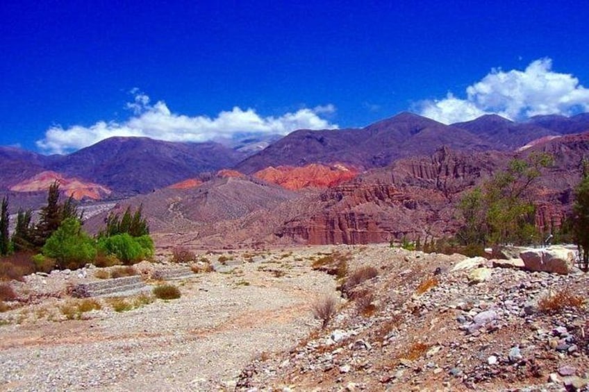 A rugged mountainous landscape with sparse vegetation and a clear blue sky. 2