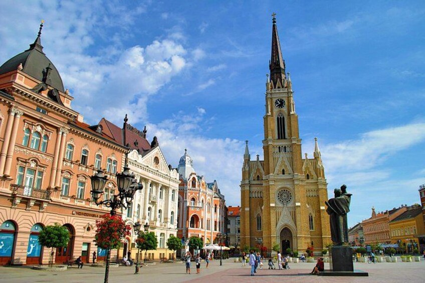 Una plaza histórica con una imponente torre de iglesia, arquitectura clásica y una estatua. 3