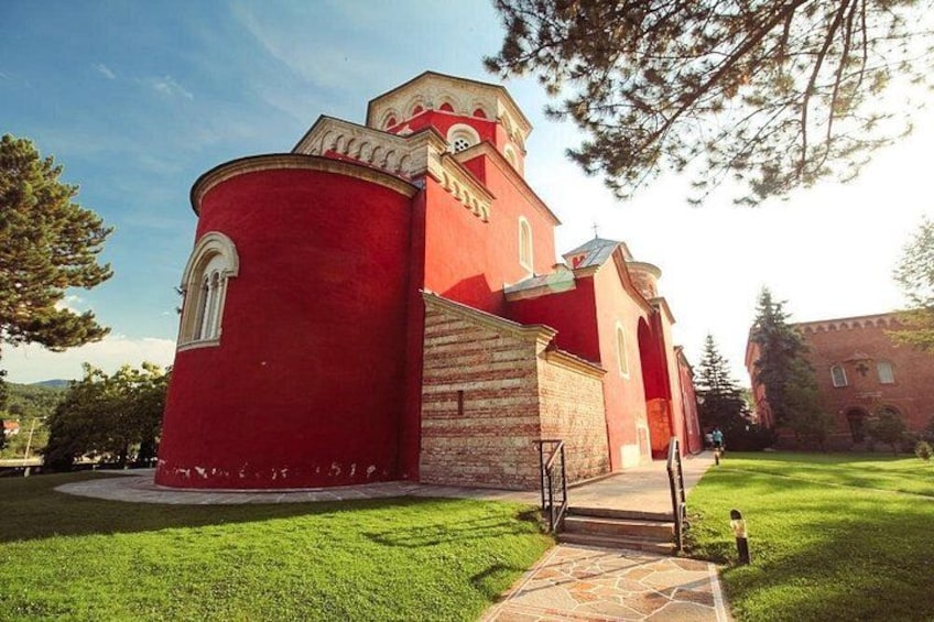 A red church with a bell tower, surrounded by a well-maintained lawn and a stone pathway leading to the entrance. 5