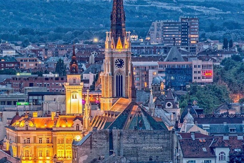 A cityscape with a prominent clock tower, a cathedral, and surrounding buildings. 2