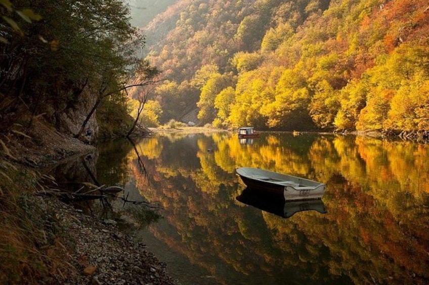 Un río tranquilo con un bote, rodeado de árboles de colores otoñales. 1