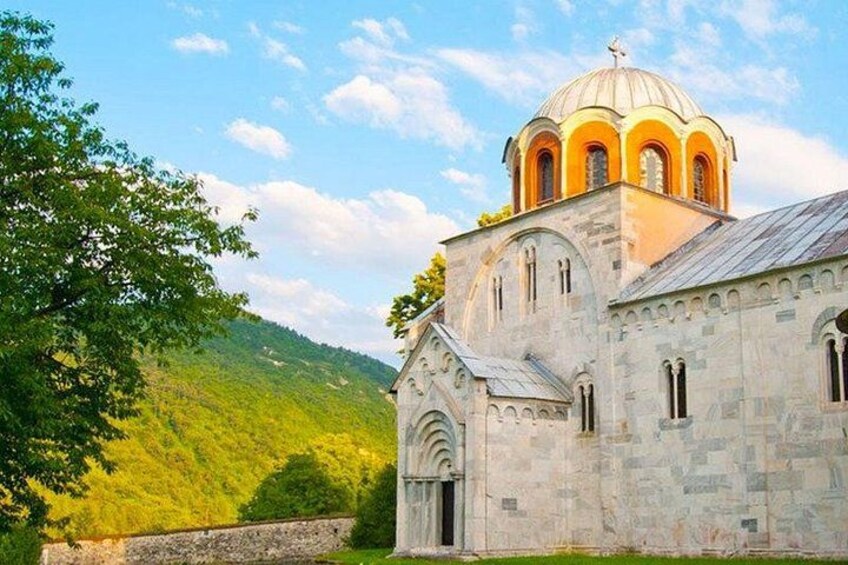 A church with a domed roof and arched windows, set against a backdrop of green hills and a clear sky. 4