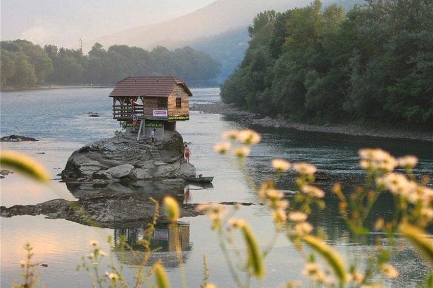 Eine hölzerne Konstruktion auf einem Felsen in einem Fluss, umgeben von viel Grün. 2