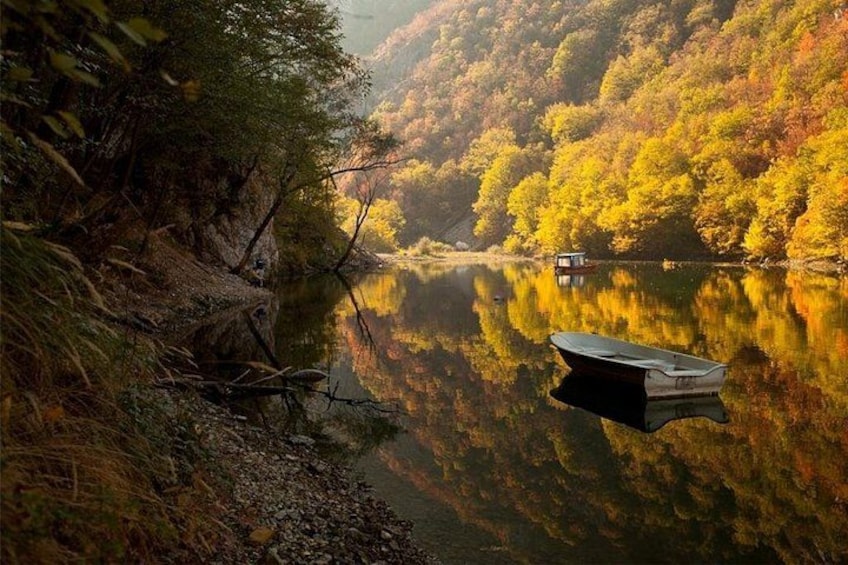 Ein ruhiger Fluss mit einem Boot, umgeben von herbstlich gefärbten Bäumen. 4