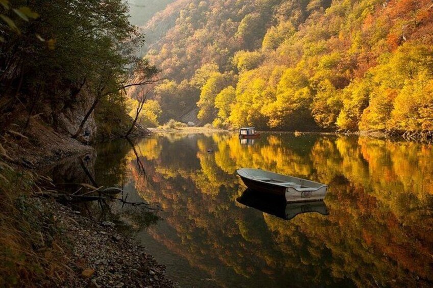 Ein ruhiger Fluss mit einem Boot, umgeben von herbstlich gefärbten Bäumen. 3