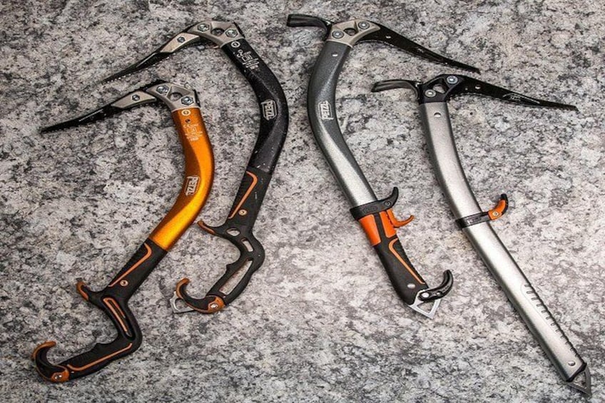 Three climbing tools with orange and black handles on a textured surface. 3