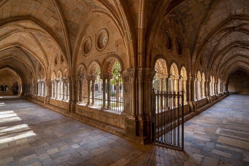 A long, arched corridor with stone columns and windows. 4