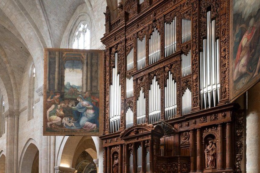An ornate pipe organ with intricate carvings and a large painting of a biblical scene. 5
