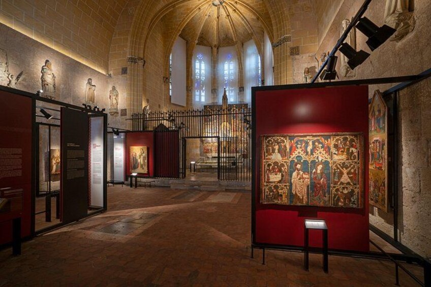 An interior of a cathedral with stone walls, a wooden floor, and a large religious painting. 3