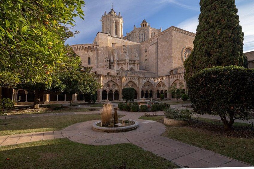 A historic building with a courtyard, a fountain, and a tall tree. 1