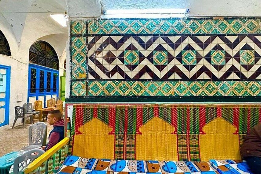Una habitación con azulejos geométricos de colores, una alfombra estampada y una puerta azul. 5