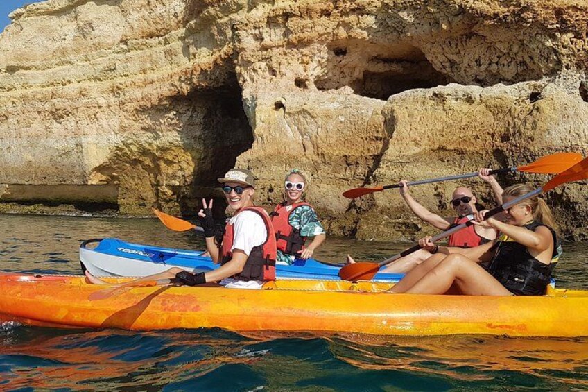 A group of people kayaking on a river with rocky cliffs in the background. 2