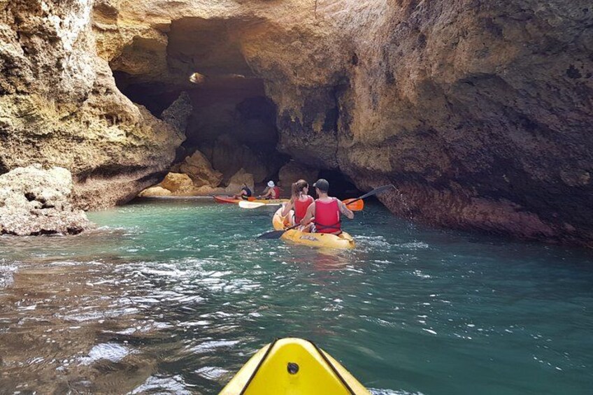 A group kayaking through a narrow water channel surrounded by rocky cliffs. 3