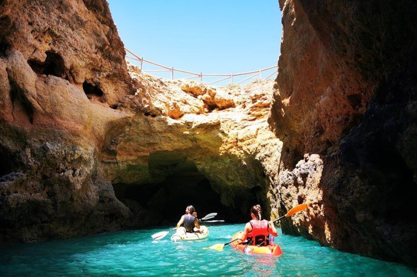 Two people kayaking in a narrow waterway between rocky cliffs. 4