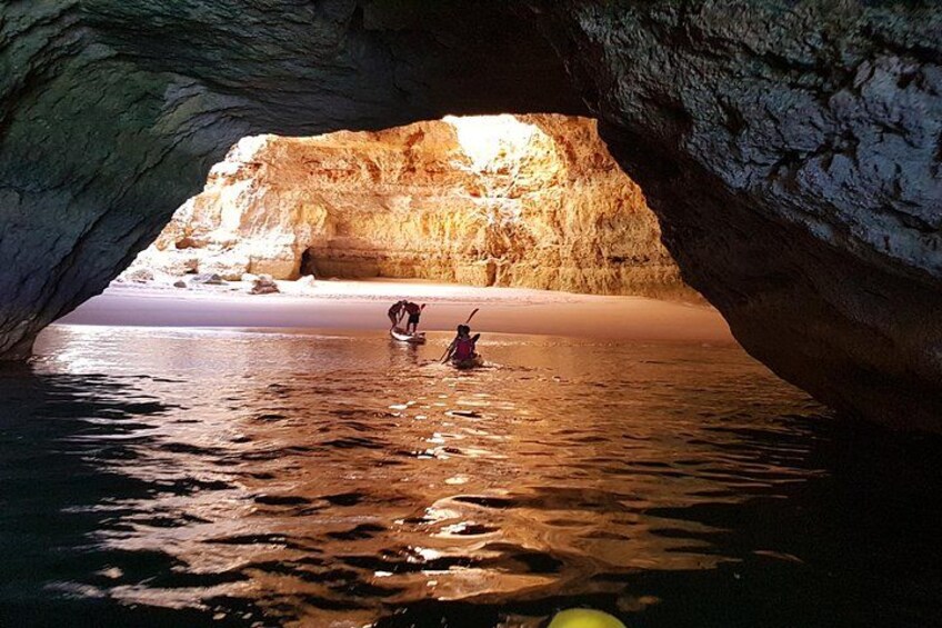 A cave opening to a beach with people in the water. 3