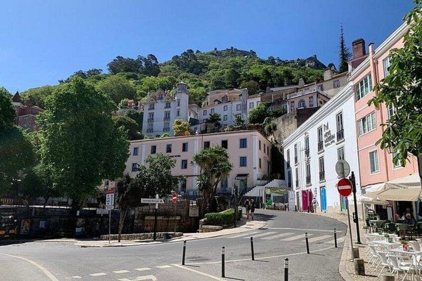 A street with buildings, a no entry sign, and a hill in the background. 3