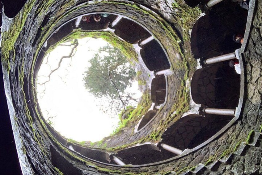A circular stone structure with a central opening, surrounded by stone benches and moss-covered walls. 3
