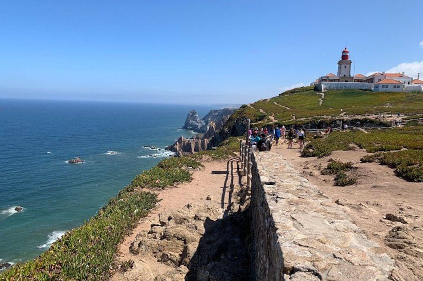 A coastal path with a lighthouse, rocky terrain, and ocean views. 5