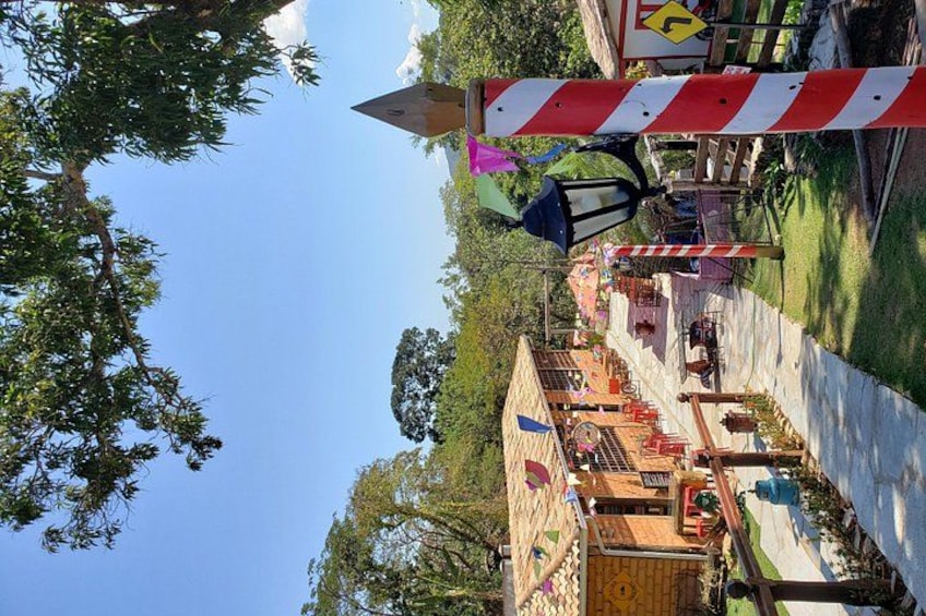A park with a red and white striped barrier, a wooden structure, and a clear blue sky. 4