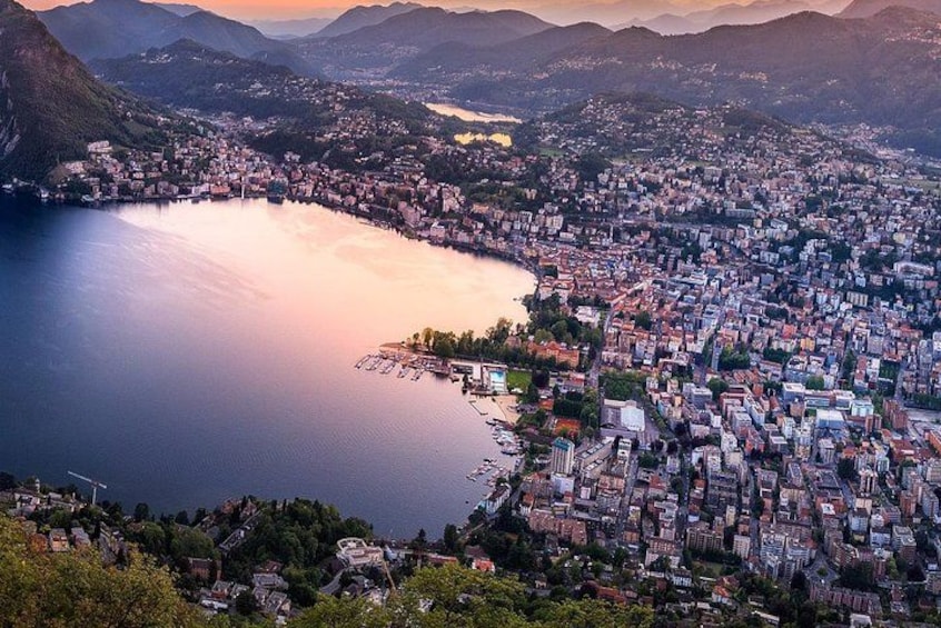 A coastal cityscape with a large body of water, dense urban area, and surrounding hills. 1