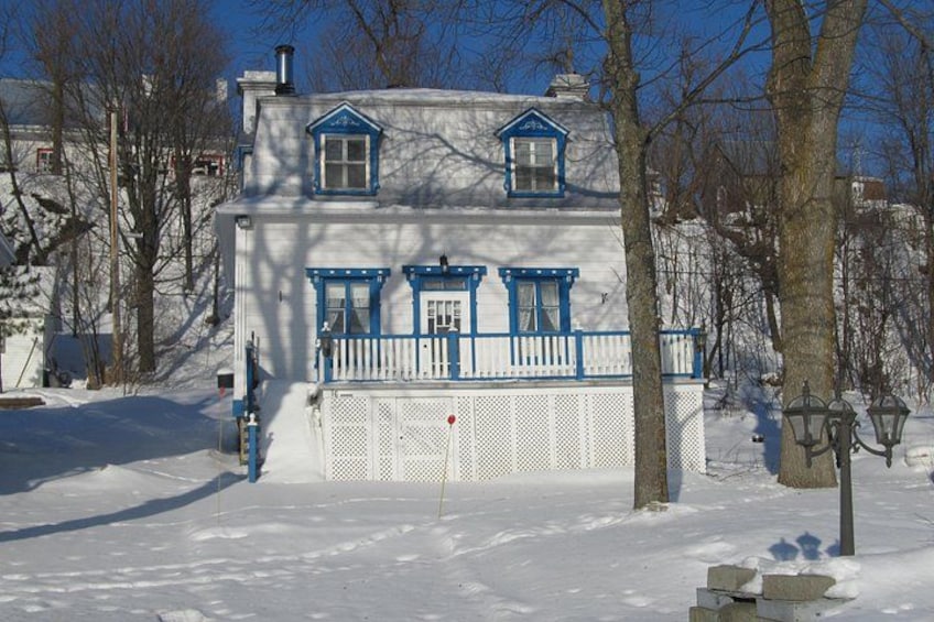 Een huis bedekt met sneeuw, met blauwe accenten en een witte hek. 2